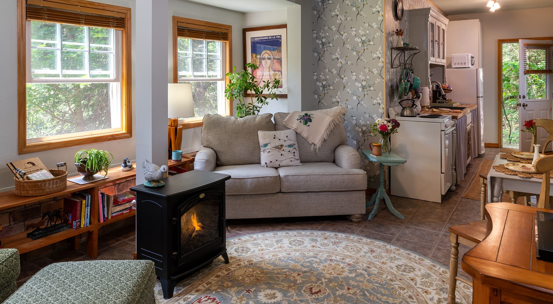 A cozy living room featuring a light gray sofa, decorative plants, and an electric fireplace.
