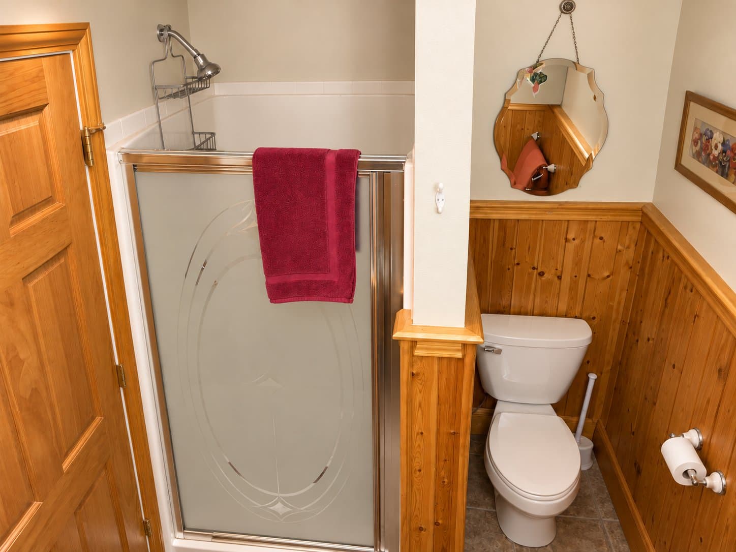 Bathroom featuring a glass shower stall with a red towel, a toilet, and wooden accents.