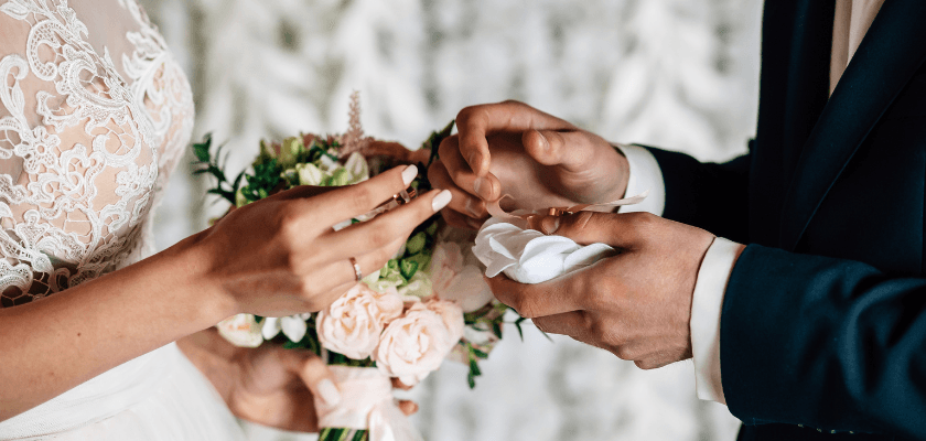A bride and groom exchange rings during their wedding ceremony. A bride and groom exchange rings during their wedding ceremony.