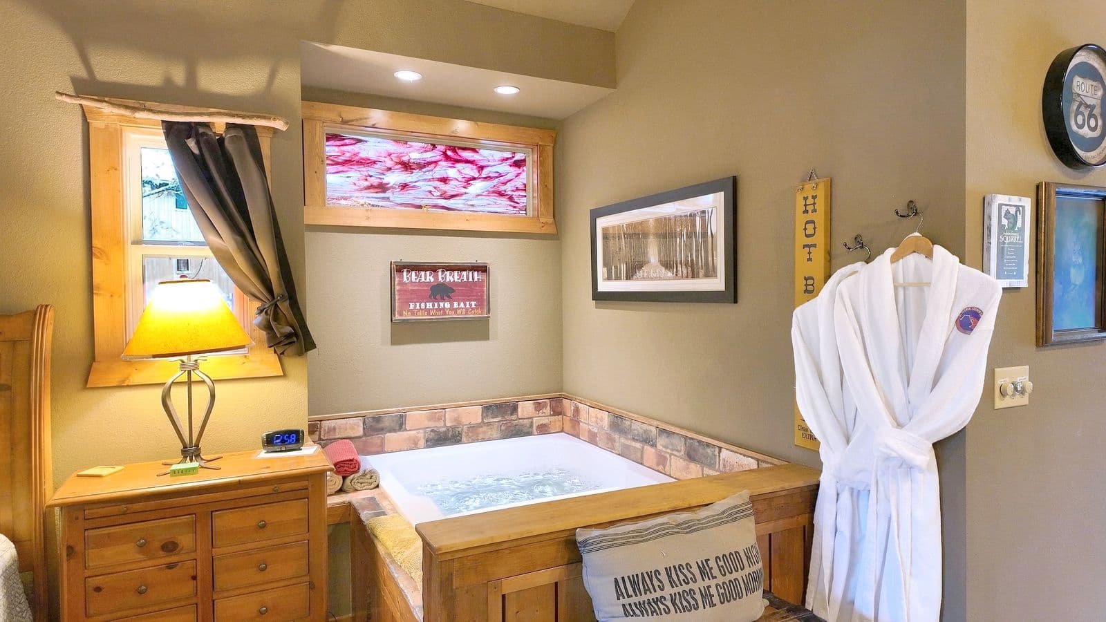 A cozy bathroom featuring a hot tub, wooden furniture, and a robe hanging nearby.