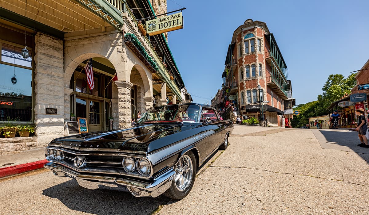 A classic black car parked on a street near a historic hotel and shops. A classic black car parked on a street near a historic hotel and shops.
