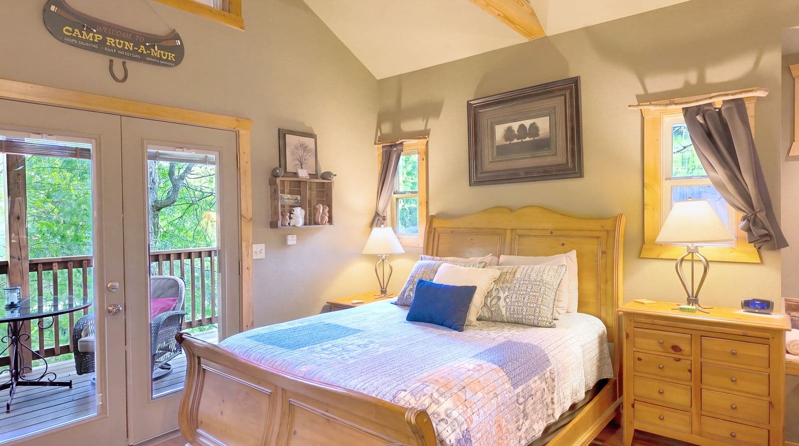 Cozy bedroom featuring a wooden bed, lamps, and access to a porch through double doors.