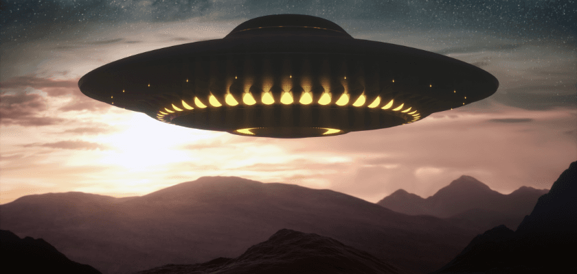 A futuristic UFO hovers over a mountainous landscape at sunset.