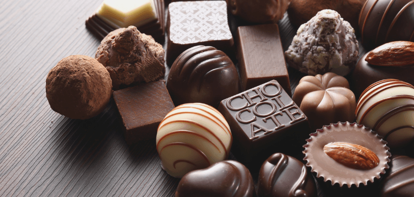 An assortment of various chocolates and truffles on a wooden surface. An assortment of various chocolates and truffles on a wooden surface.