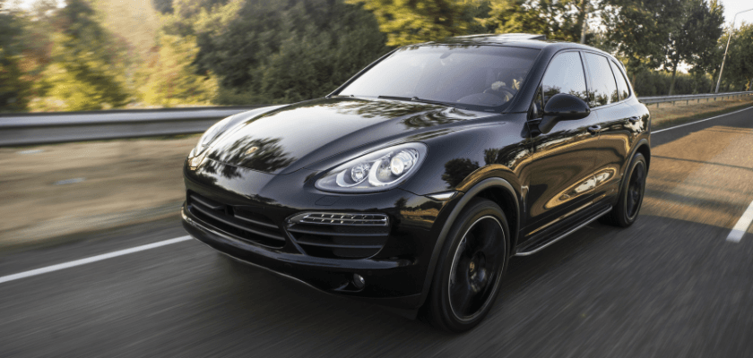 A sleek black SUV drives along a tree-lined road. A sleek black SUV drives along a tree-lined road.