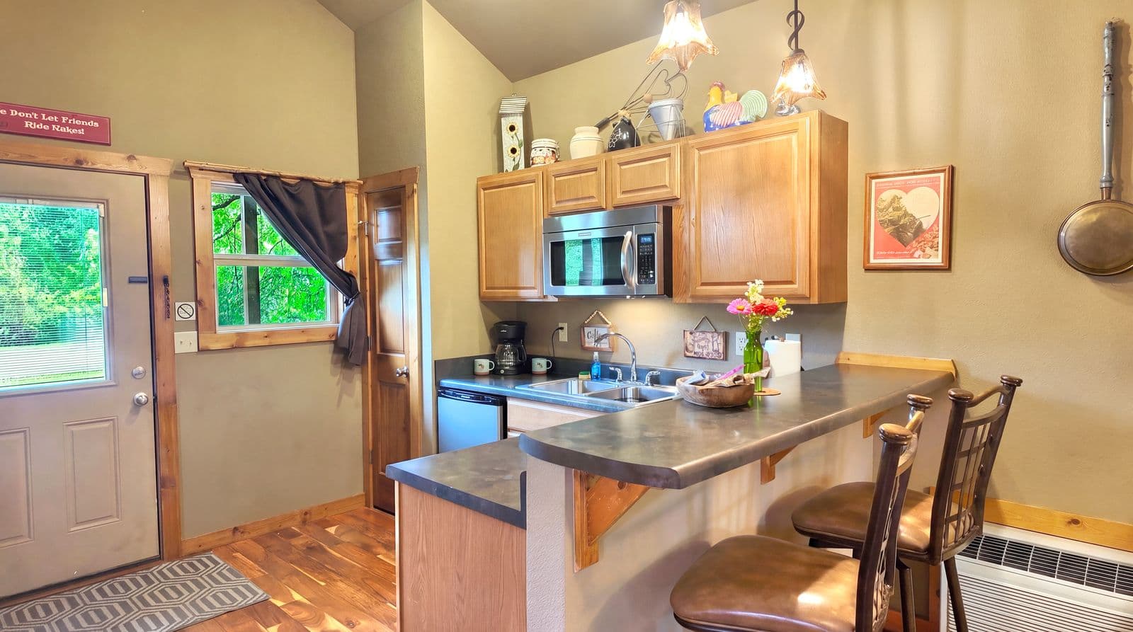 Cozy kitchen featuring wooden cabinets, modern appliances, and a small dining area with bar stools.