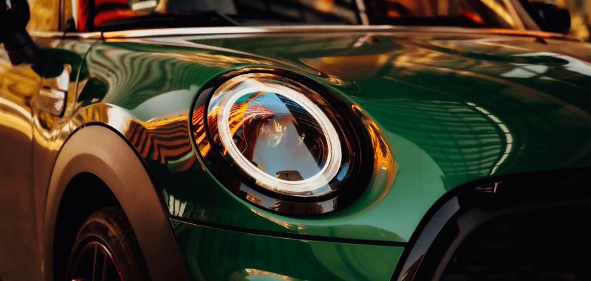 Close-up of a green car's headlight reflecting ambient light. Close-up of a green car's headlight reflecting ambient light.