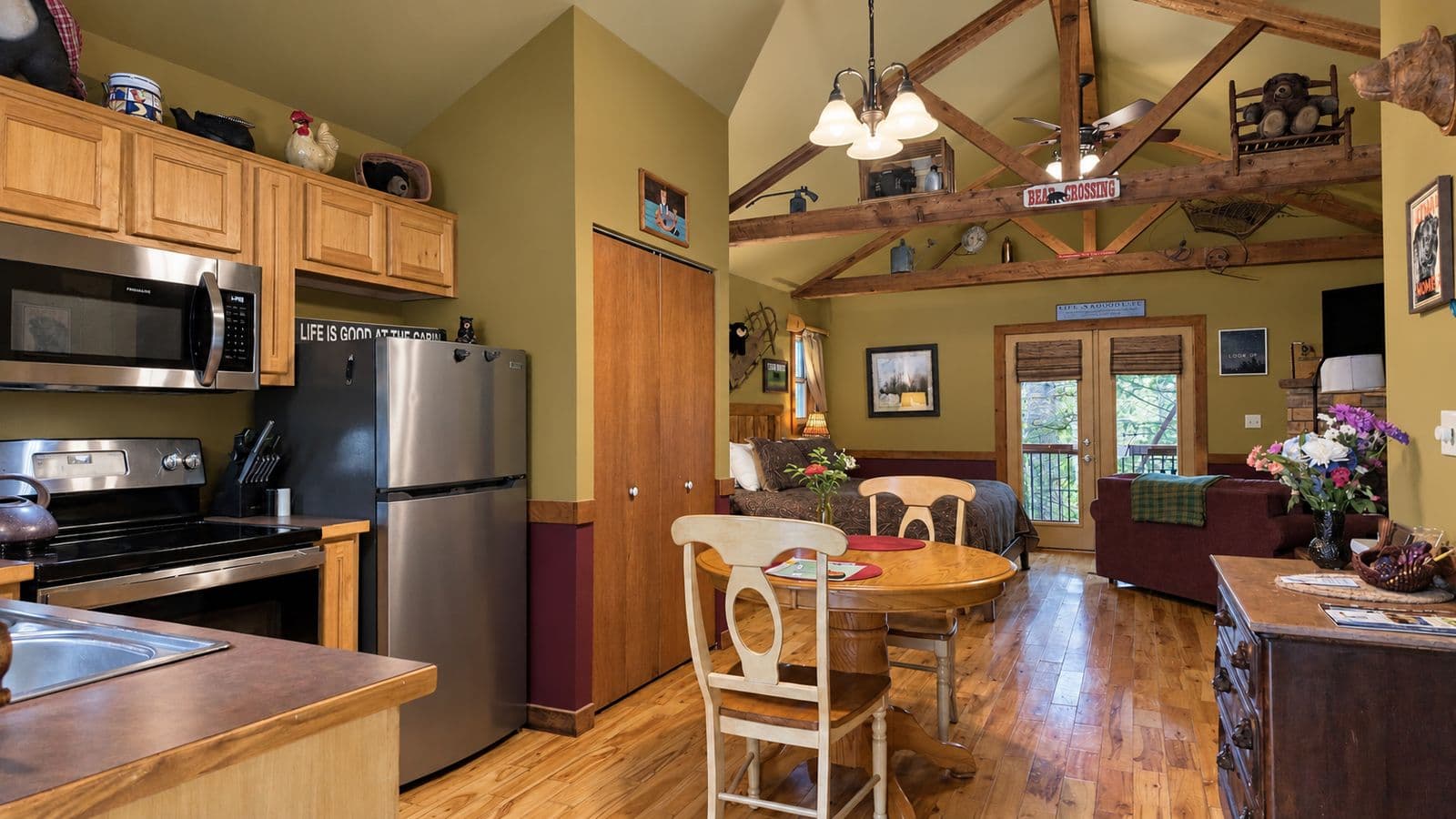 A cozy kitchen and dining area with wooden cabinets, a round table, and a living space featuring a rustic decor.