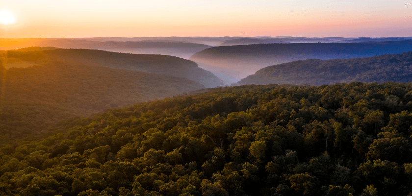 Aerial view of a lush green valley surrounded by misty hills at sunrise. Aerial view of a lush green valley surrounded by misty hills at sunrise.