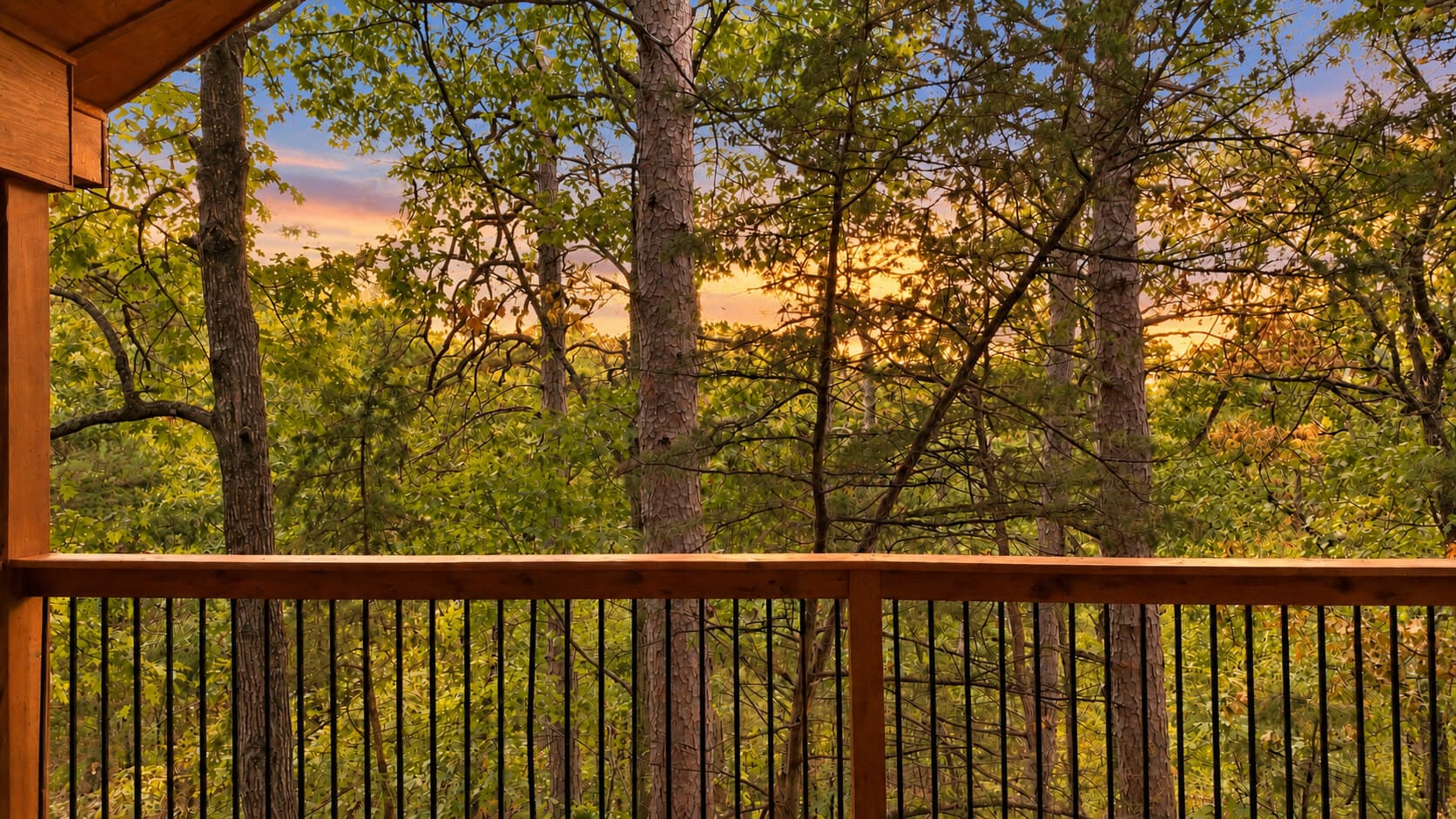 View of a forest at sunset from a wooden balcony.