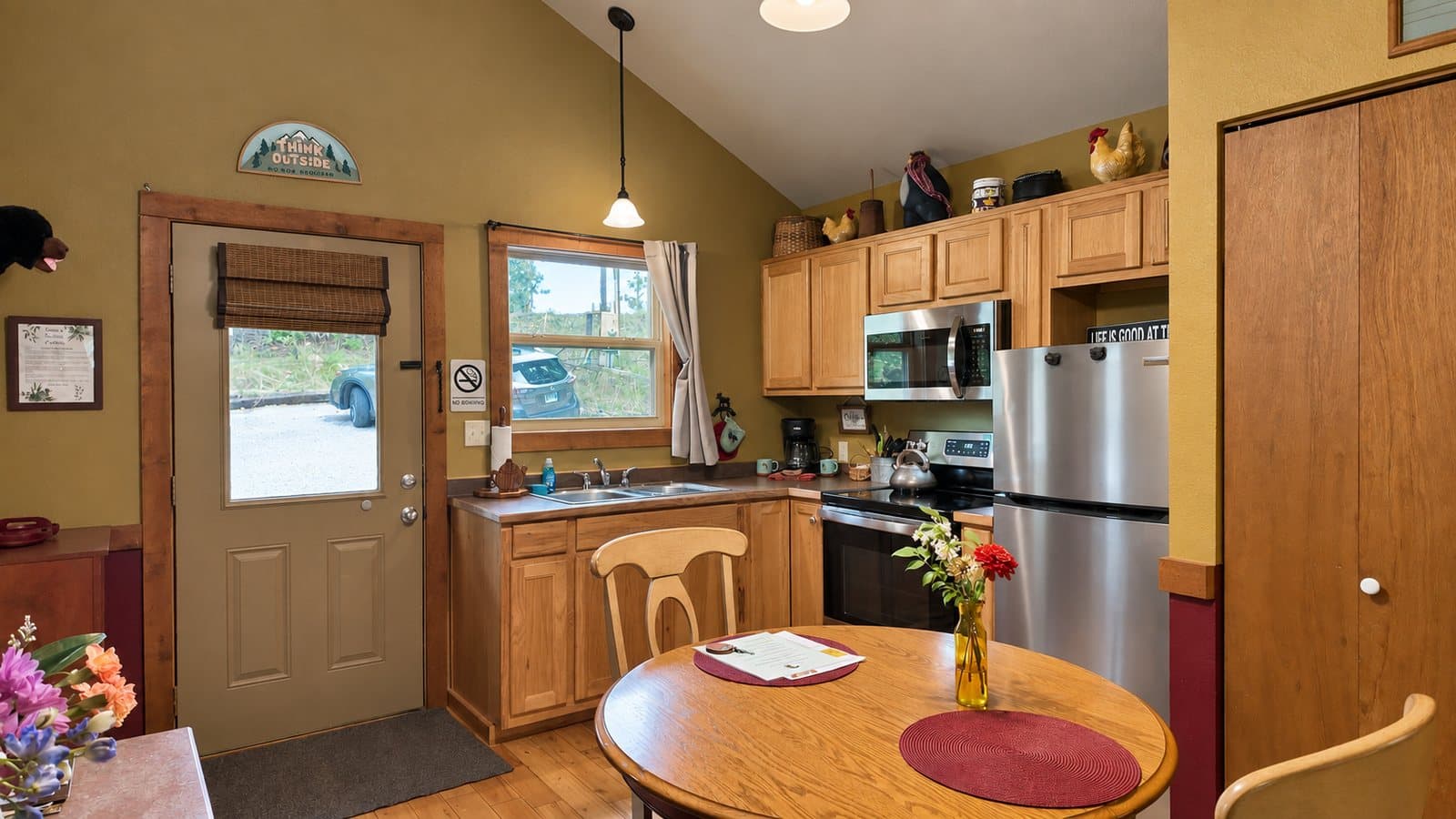 A cozy kitchen featuring wooden cabinets, a round dining table, and a door leading to an outdoor view.