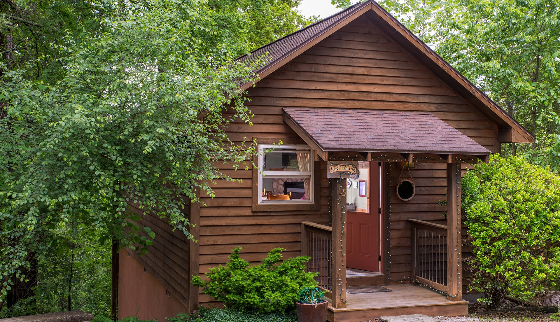 A rustic wooden cottage surrounded by lush green foliage.