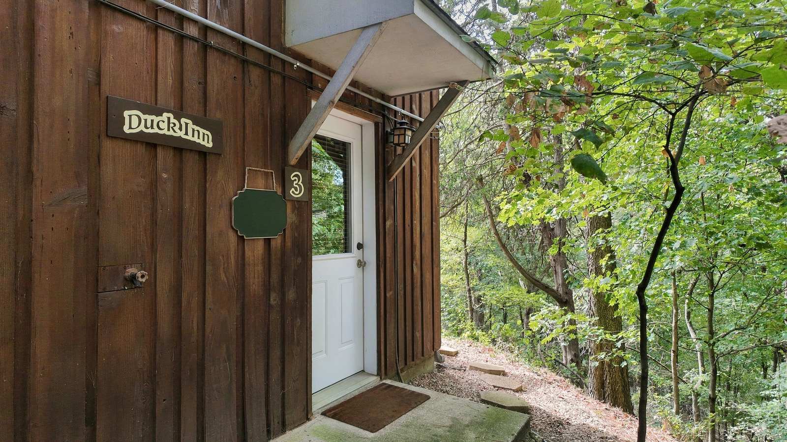Entrance to the Duck Inn cabin surrounded by trees.