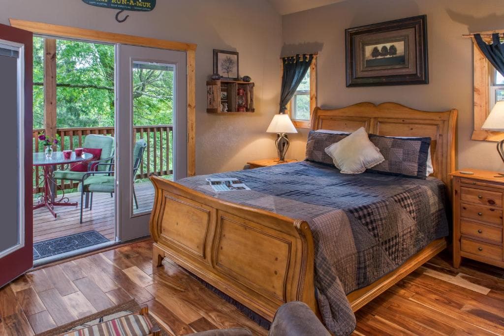 Cozy bedroom featuring a wooden bed, warm lighting, and patio doors leading to an outdoor deck.