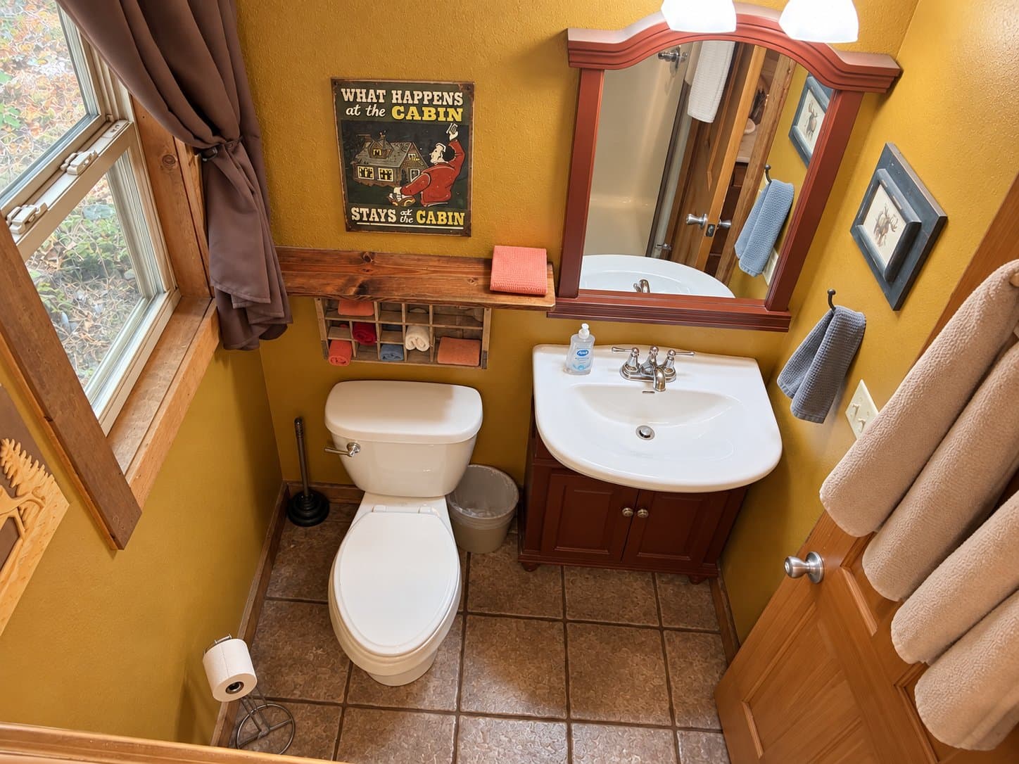 A cozy bathroom featuring a toilet, sink, and wooden accents with a rustic wall hanging.