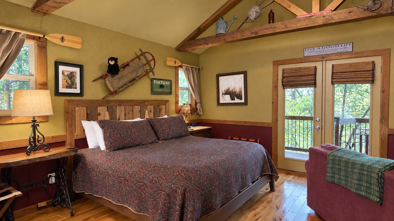 A cozy bedroom with a wooden bed, warm decor, and large windows overlooking nature.