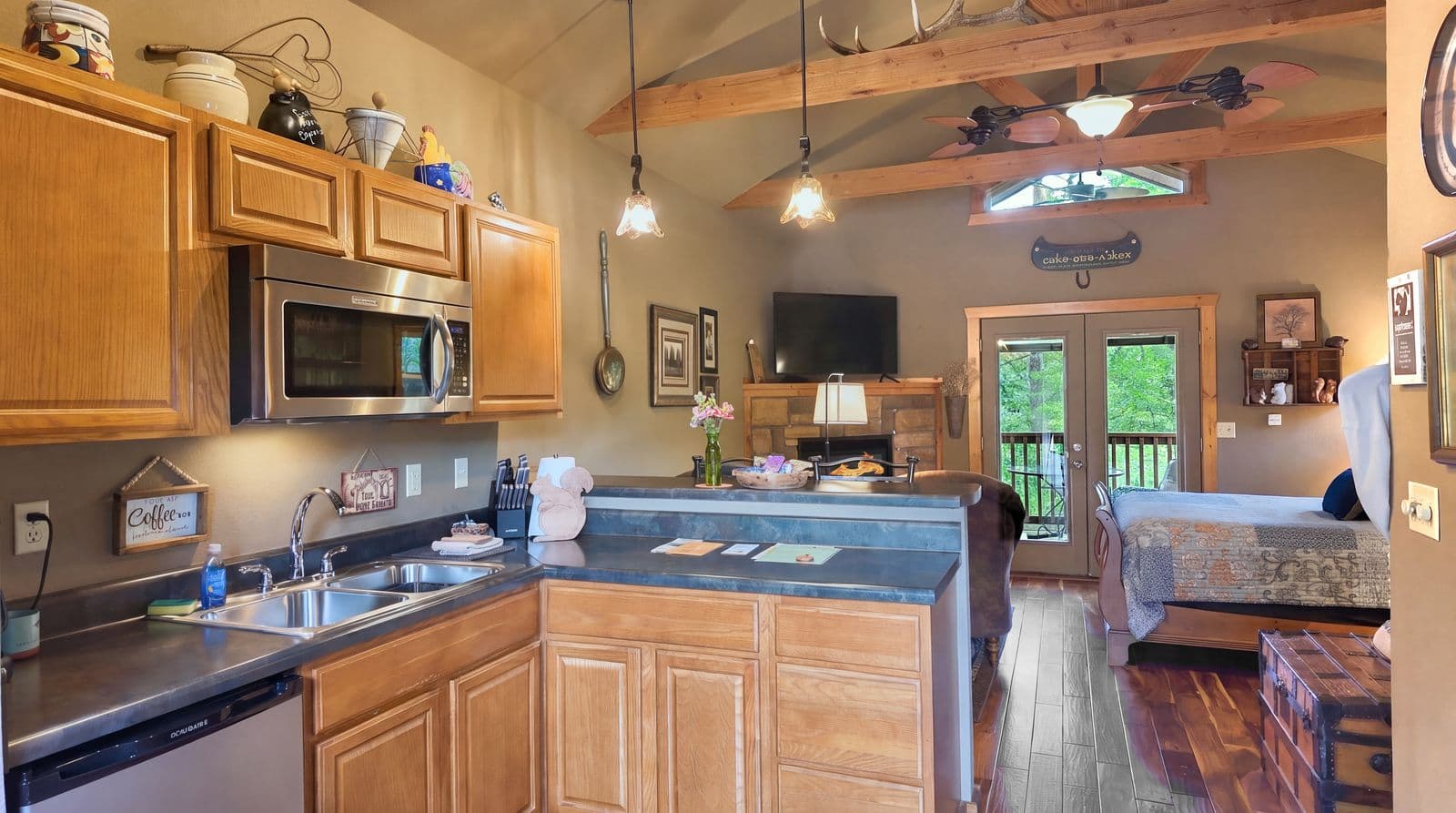 Cozy kitchen and living area with wooden cabinets, modern appliances, and large windows overlooking a deck.