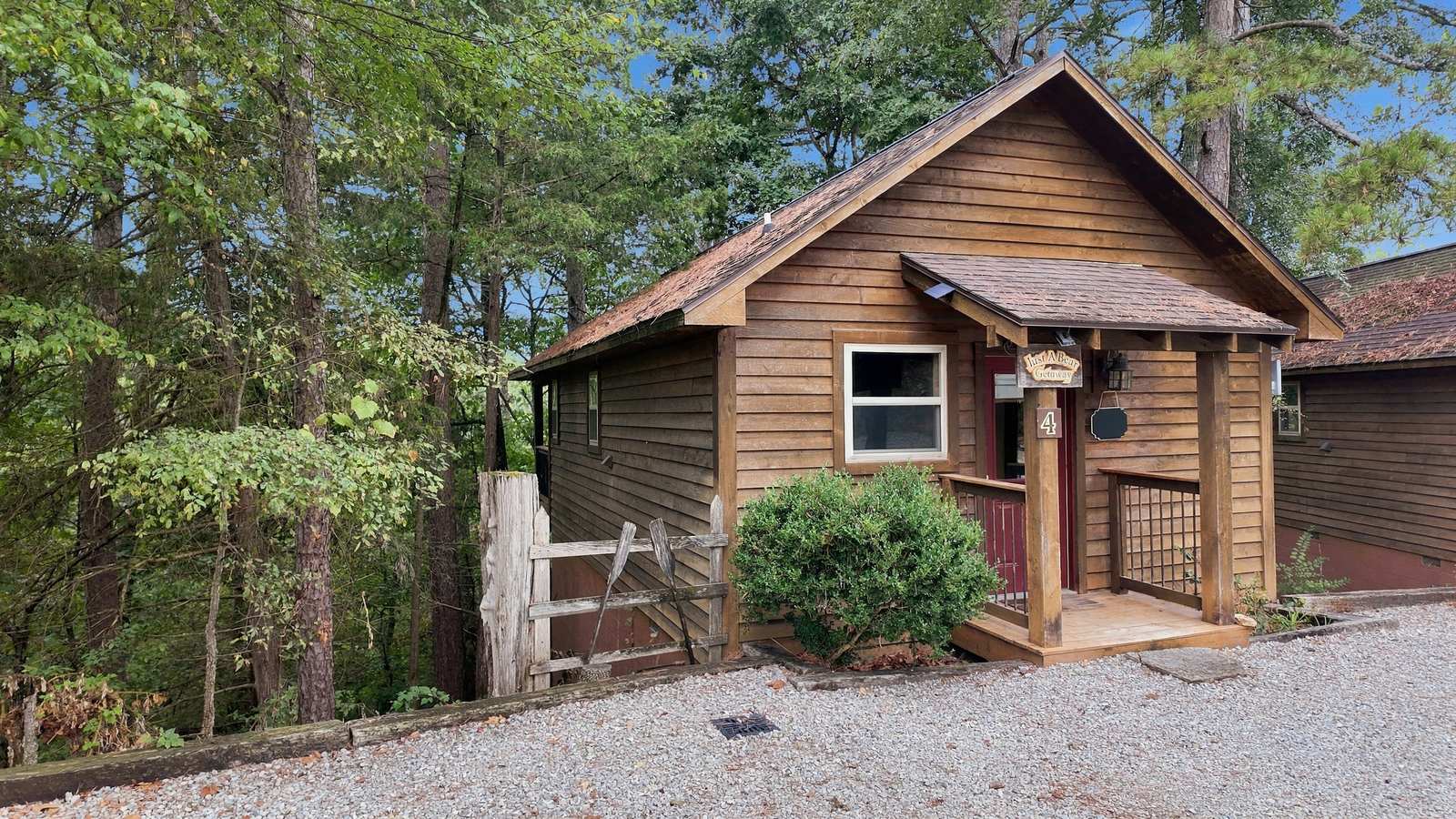 A cozy wooden cabin nestled among trees with a gravel pathway.