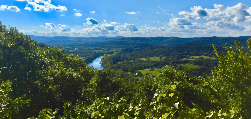 Panoramic view of green hills and a winding river under a blue sky with clouds. Panoramic view of green hills and a winding river under a blue sky with clouds.