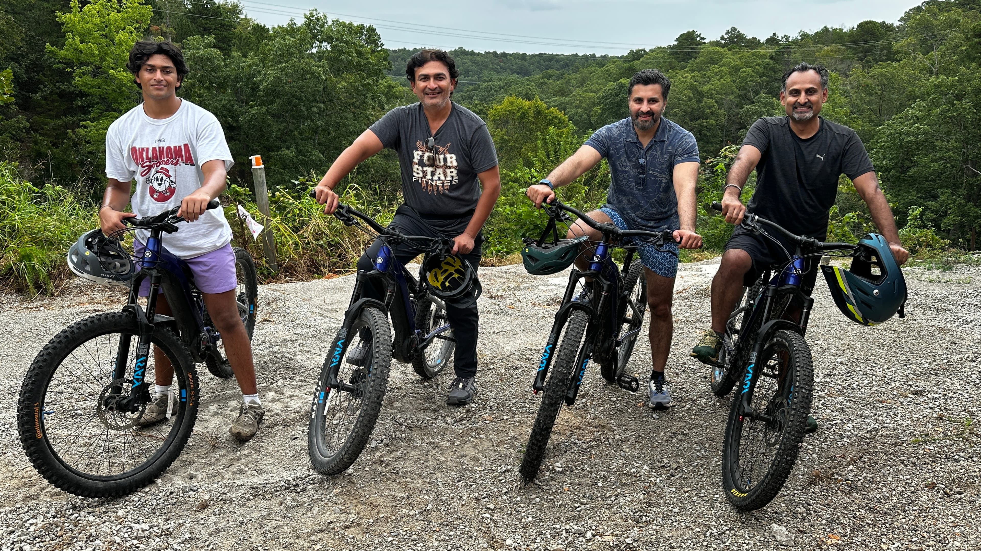 Four men posing with mountain bikes against a lush green landscape.