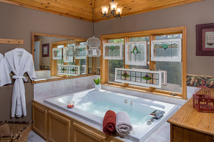 A sunny bathroom featuring a jacuzzi, wooden accents, and soft towels neatly arranged.