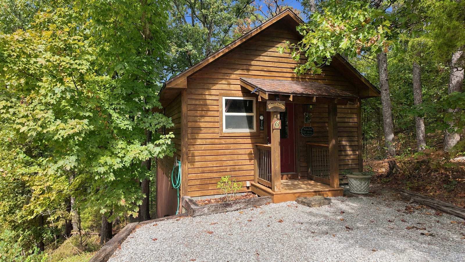 A small wooden cabin surrounded by trees and gravel pathways.