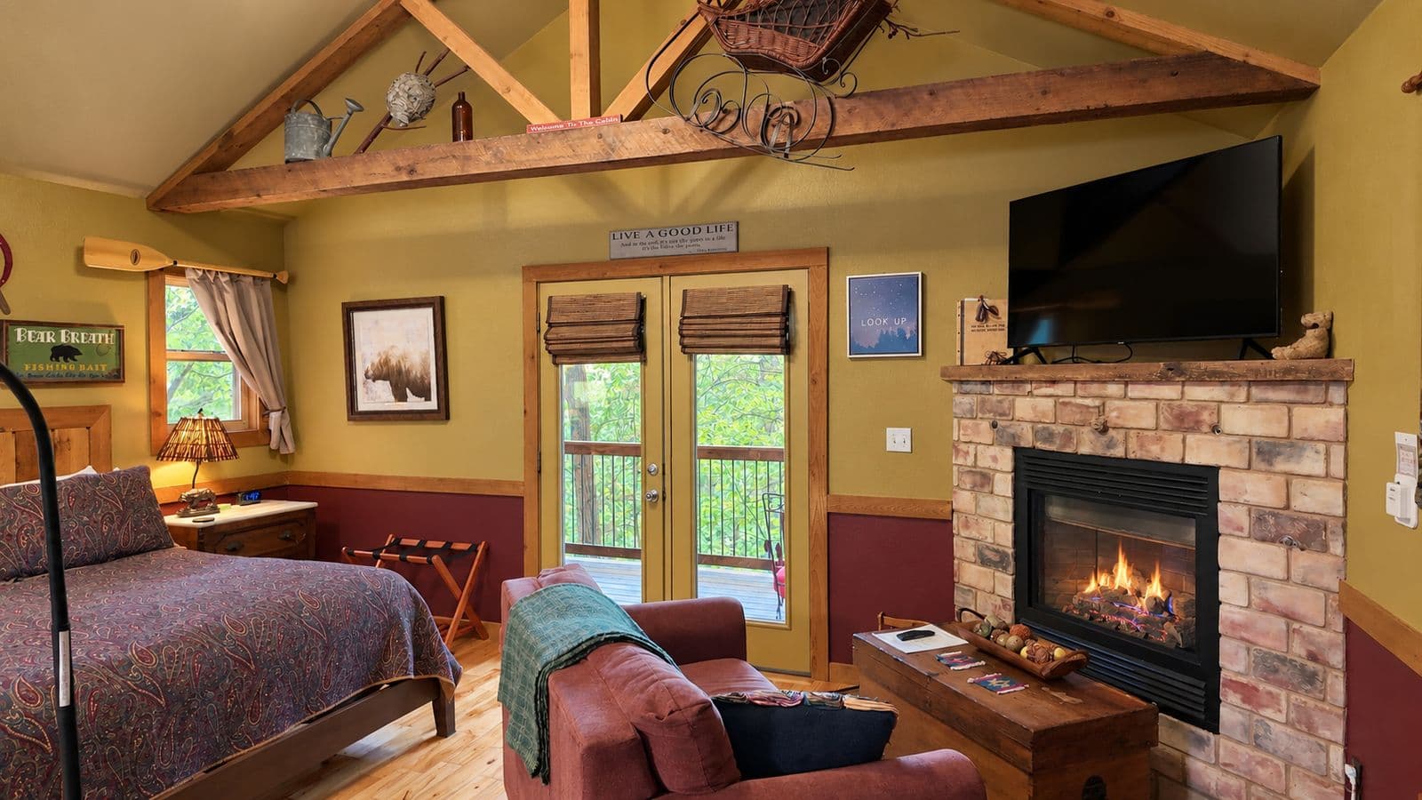 Cozy cabin interior featuring a bed, fireplace, television, and large windows with a view.