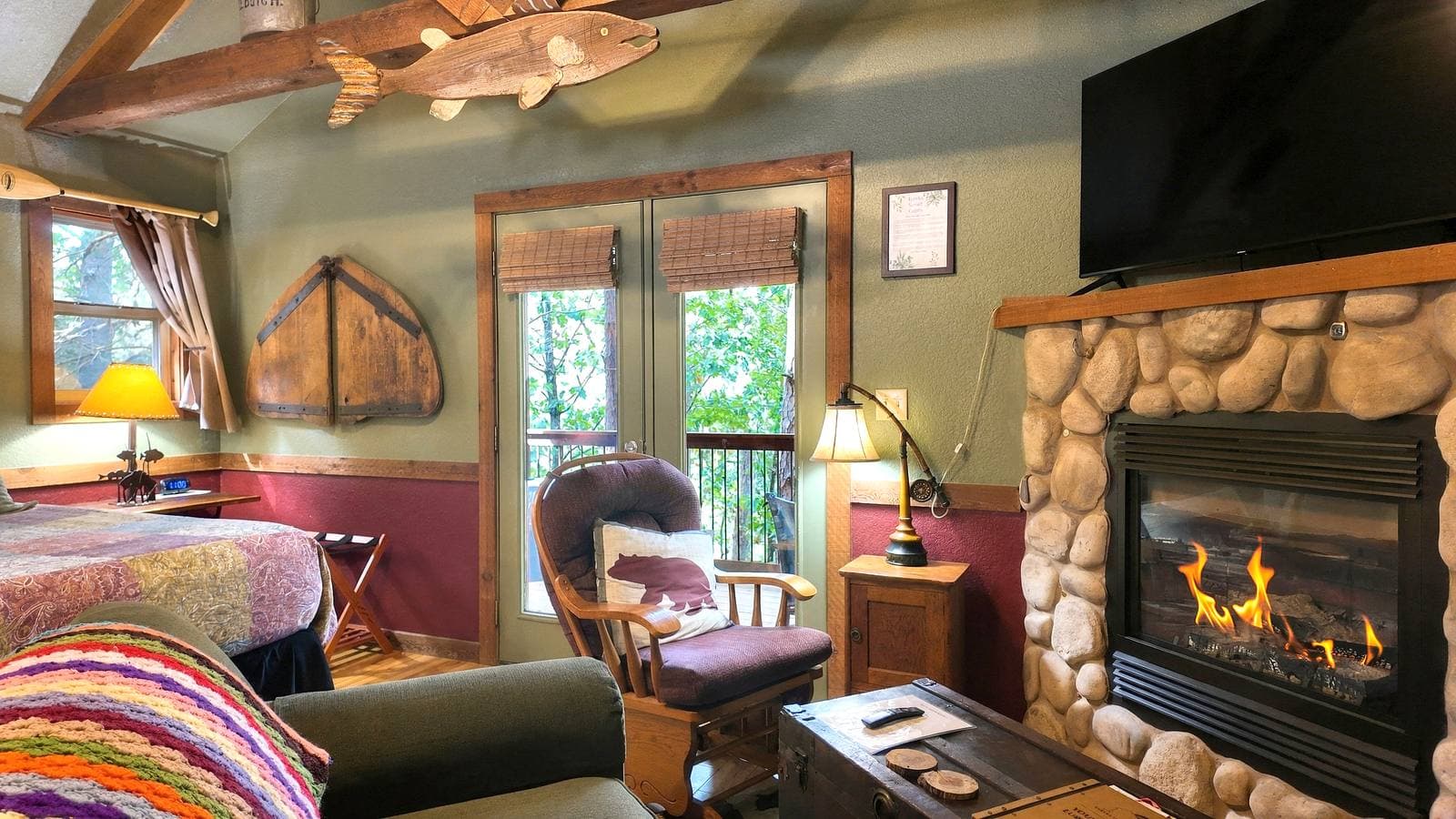 Cozy cabin interior featuring a stone fireplace, comfortable seating, and large windows.