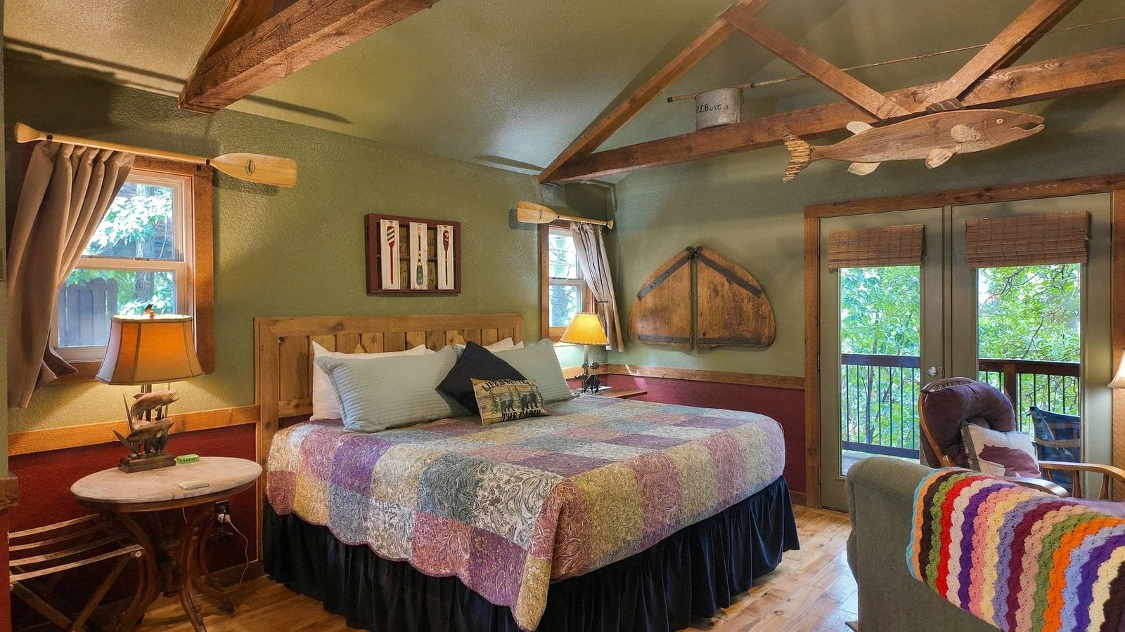 A cozy bedroom featuring a large quilted bed, wooden beams, and a warm color palette.