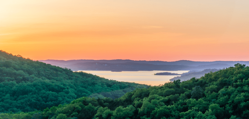 A serene landscape at sunset featuring rolling green hills and a tranquil lake. A serene landscape at sunset featuring rolling green hills and a tranquil lake.