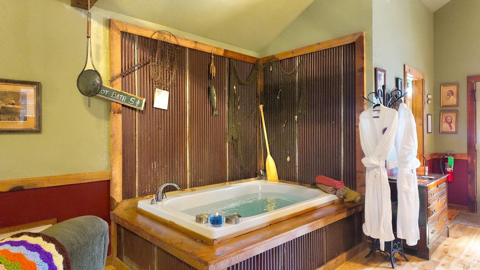 A cozy bathroom featuring a large soaking tub, rustic decor, and a plush white robe.
