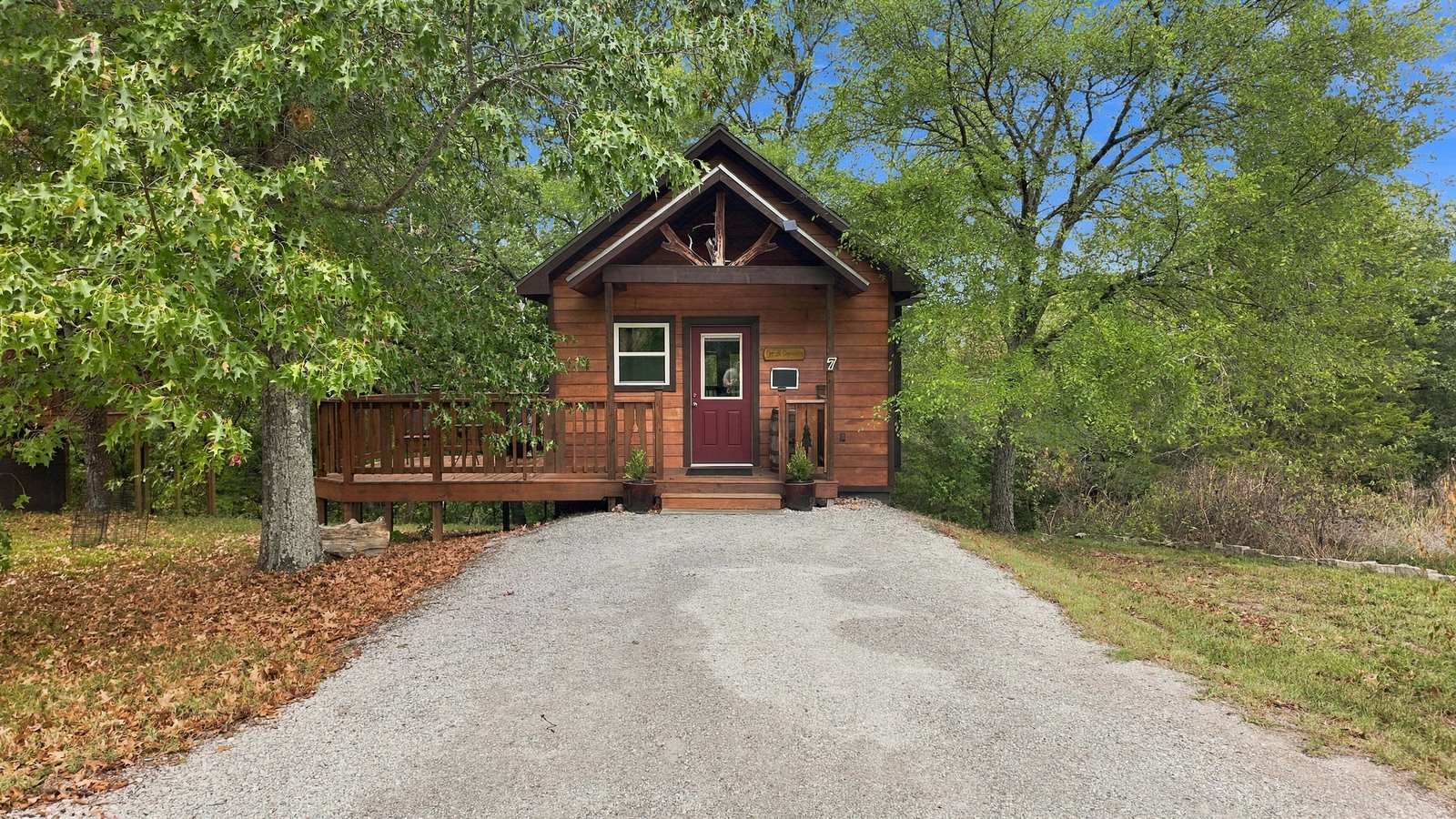 A rustic wooden cabin with a front porch nestled among trees.