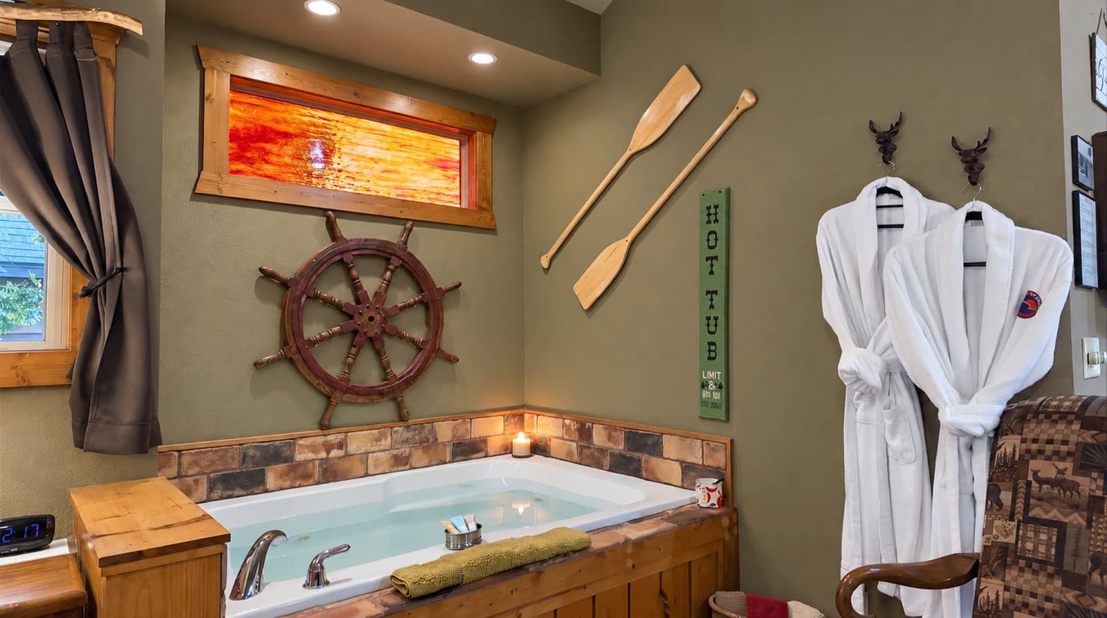 A cozy bathroom featuring a hot tub, nautical decor, and plush white bathrobes.