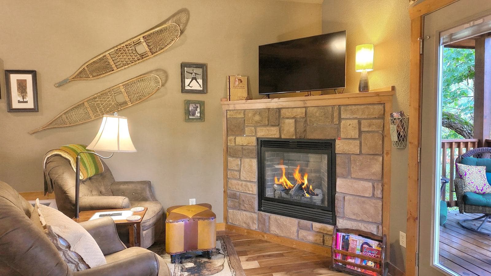 Cozy living room featuring a stone fireplace, comfortable seating, and decorative snowshoes on the wall.