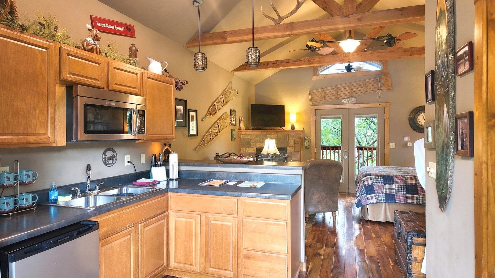 A cozy kitchen and living area featuring wooden cabinets, modern appliances, and large windows overlooking a deck.