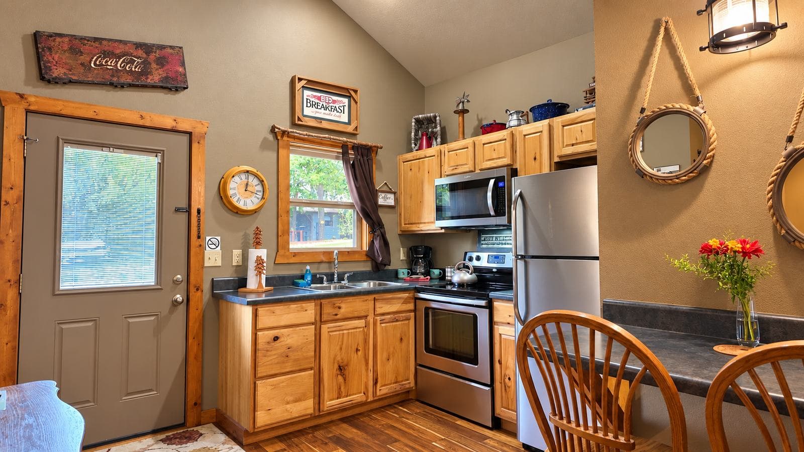 Cozy kitchen with wooden cabinets, stainless steel appliances, and a dining area featuring round chairs.