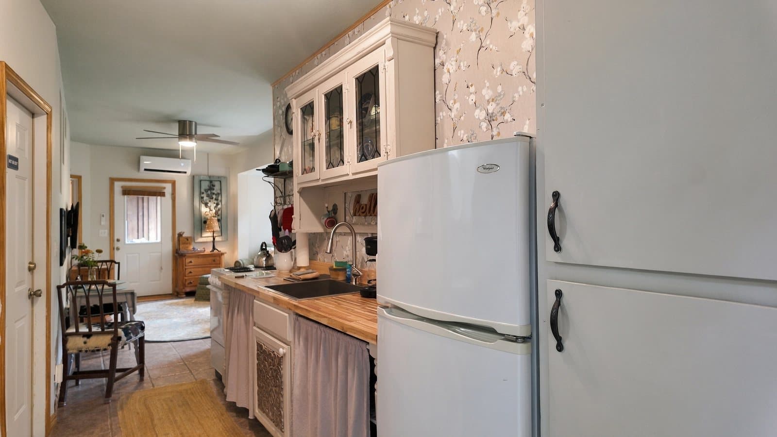 A cozy kitchen featuring white cabinets, a wooden countertop, and an adjacent dining area.