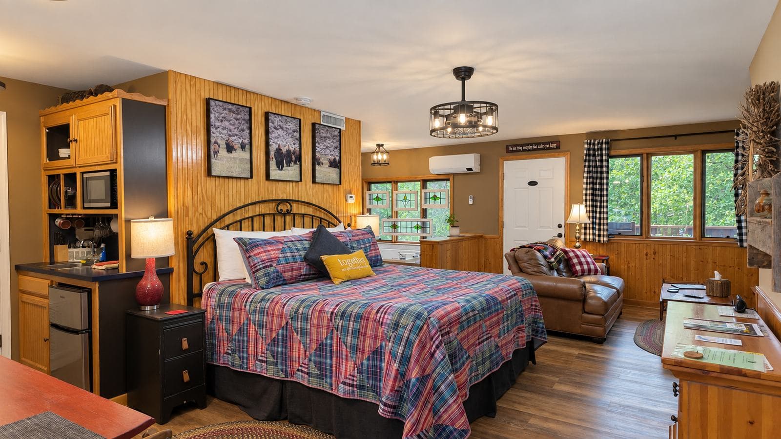 Cozy bedroom featuring a plaid bedspread, wooden accents, and large windows with natural light.