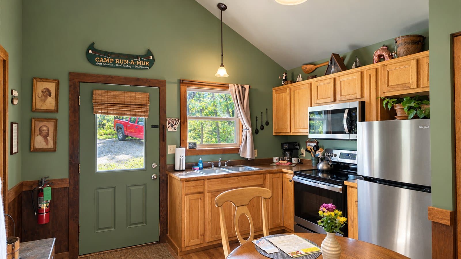 A cozy, rustic kitchen with wooden cabinets, modern appliances, and a dining table by the window.