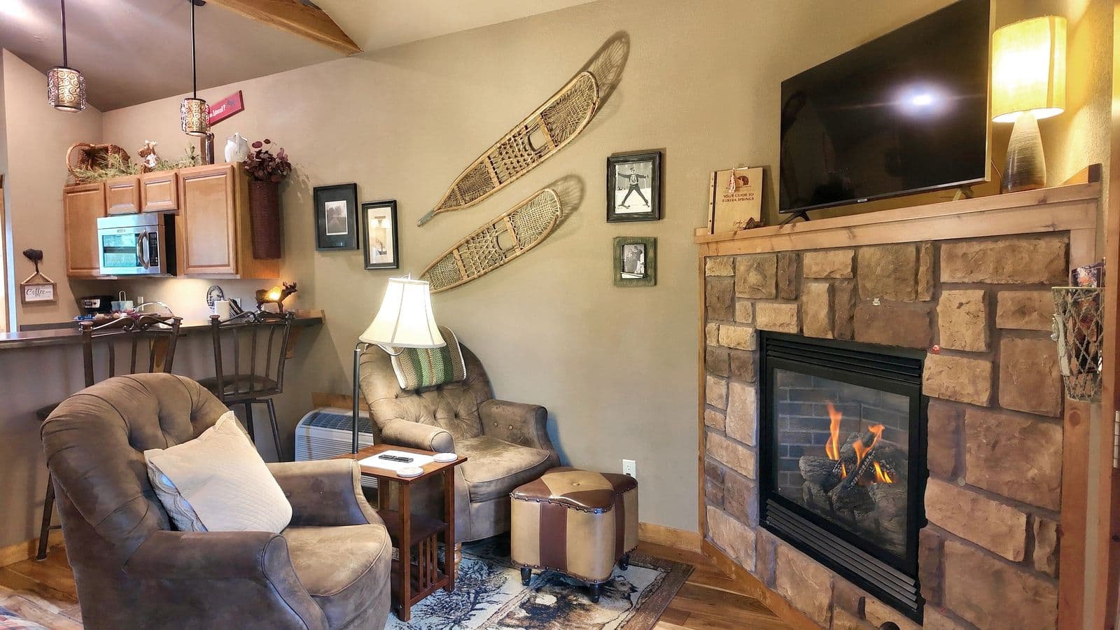 A cozy living room features a stone fireplace, comfortable seating, and rustic decor.